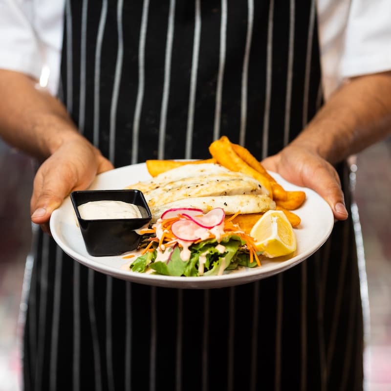 Photo of man holding place ofr fish, salad and plantains